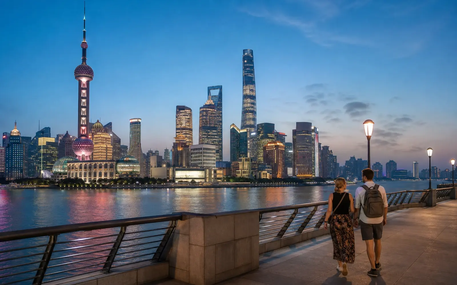 The Bund promenade at dusk, the lit towers of Pudong across the Huangpu River