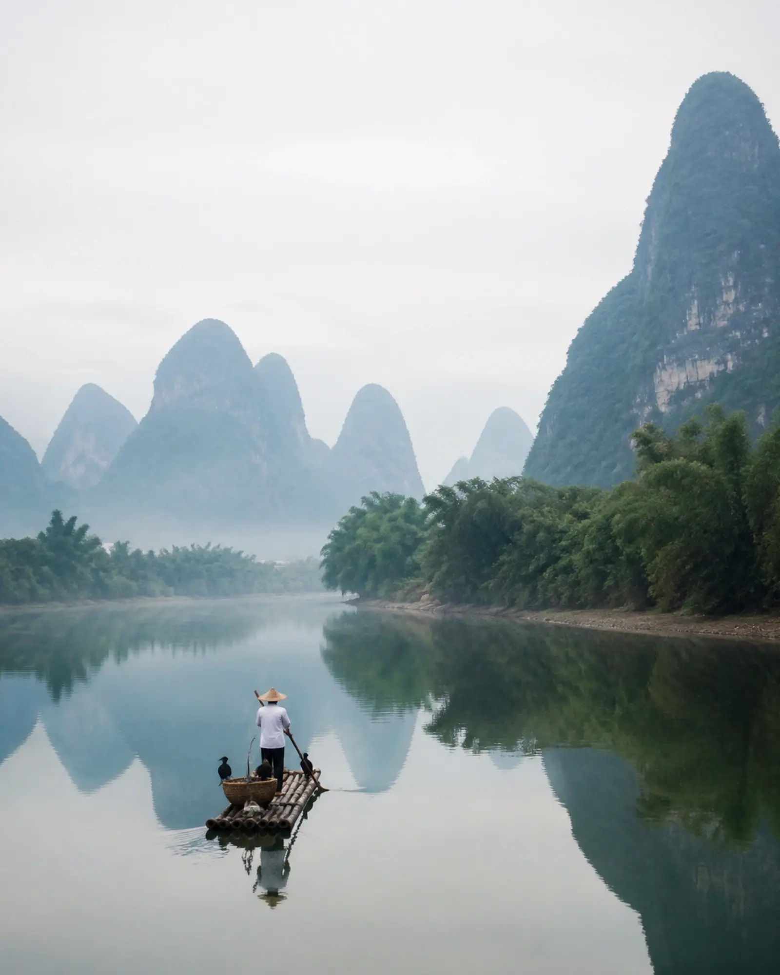 Karst peaks of the Li River receding in morning mist, a bamboo raft below
