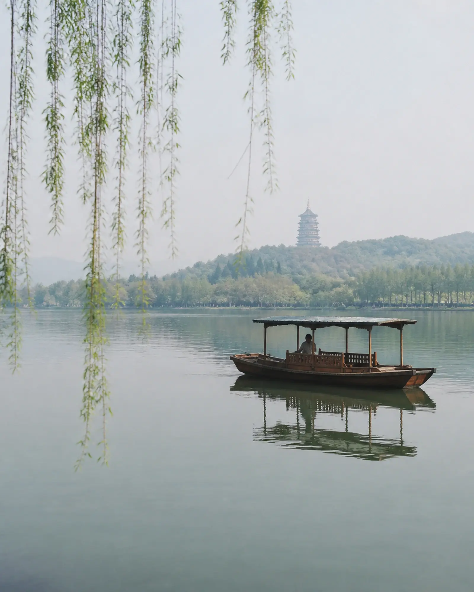 West Lake on a still morning, willows trailing and a wooden boat mid-lake